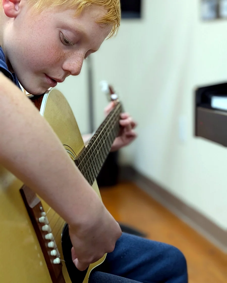 Close-up of a student focused on acoustic guitar